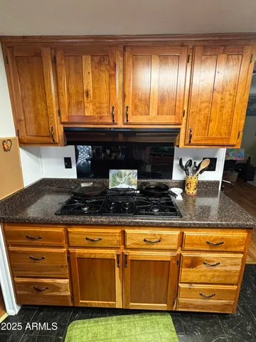 a kitchen with granite countertop a stove a sink and white cabinets