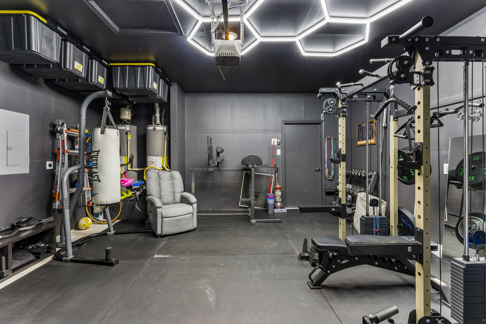 343 Sickle Loop Kyle, TX 78640 - Photo 34 of 40 Dedicated fitness space featuring rubber flooring, overhead hexagonal lighting, and a dark, monochromatic color scheme