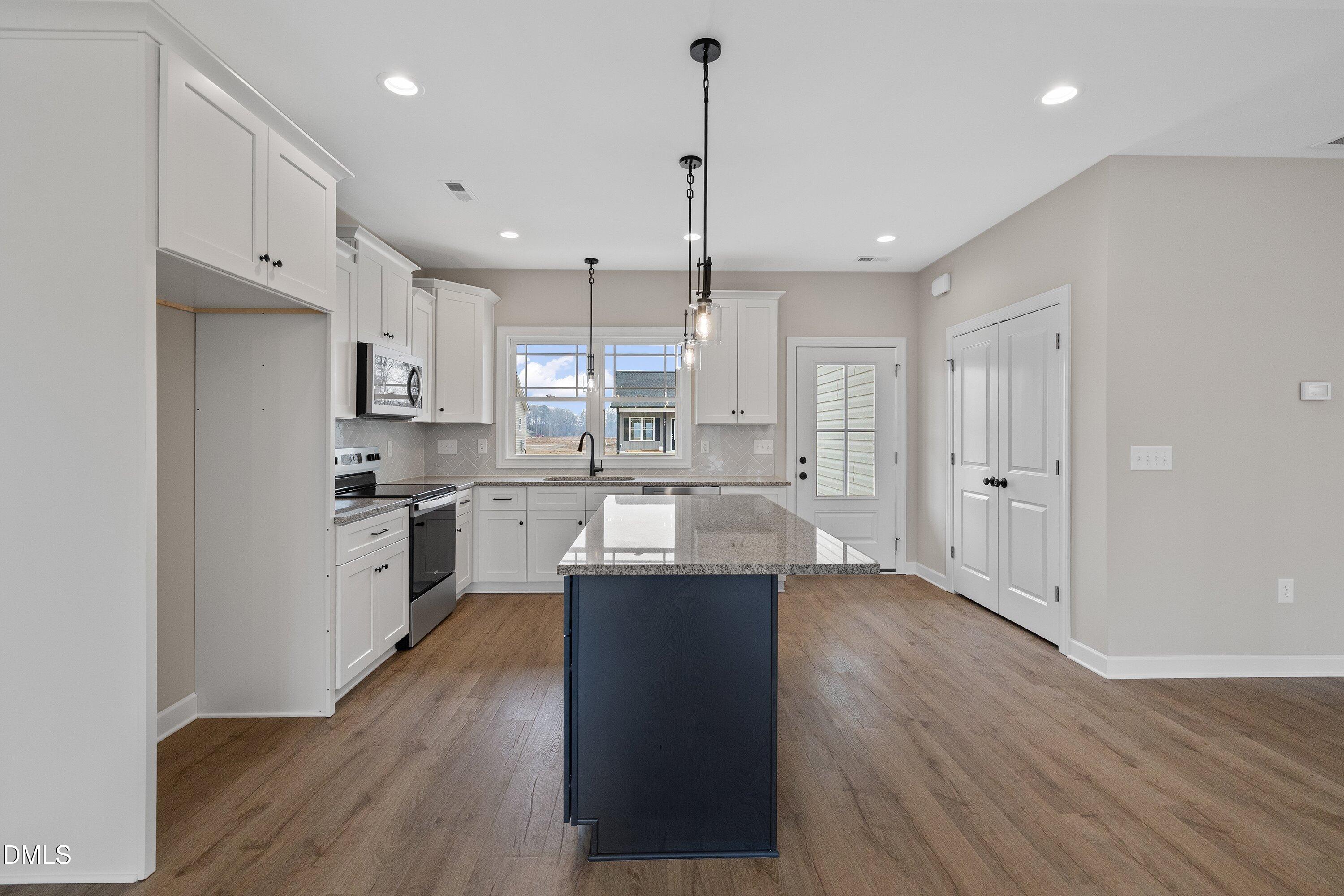 922 Micro Road West Selma, NC 27576 - Photo 6 of 36 a large kitchen with a center island wooden floor stainless steel appliances and cabinets
