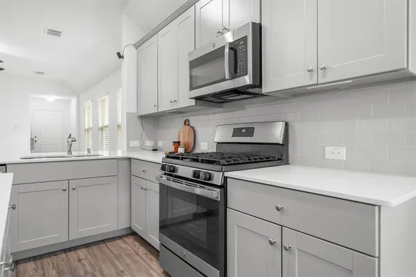 a kitchen with stainless steel appliances granite countertop white cabinets a stove a sink and dishwasher