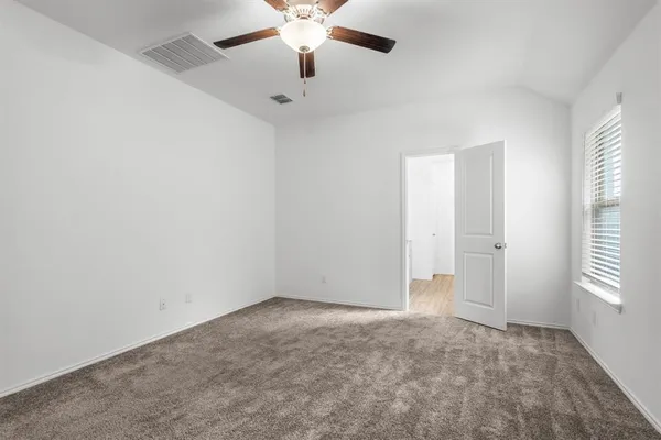 an empty room with windows and fan
