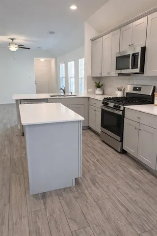 a kitchen with stainless steel appliances a stove top oven a sink and a microwave