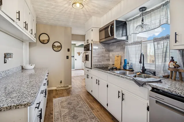a kitchen with stainless steel appliances granite countertop a lot of counter space and wooden floor