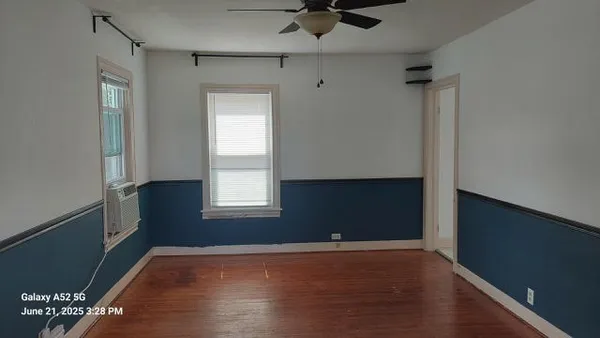 a view of an empty room with a window and wooden floor