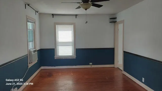 a view of an empty room with a window and wooden floor