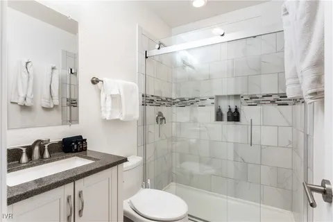 a bathroom with a granite countertop sink a toilet and shower