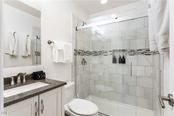 a bathroom with a granite countertop sink a toilet and shower
