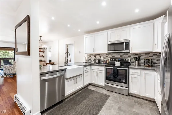 a kitchen with stainless steel appliances granite countertop a stove top oven a sink and a refrigerator