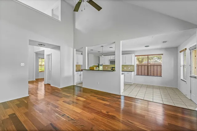 a view of an empty room with kitchen and window