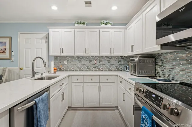 a kitchen with white cabinets a sink stove and microwave