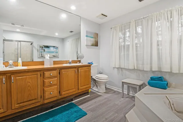 a spacious bathroom with a double vanity sink a mirror and a toilet