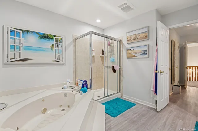 a bathroom with a tub a window and a glass door shower