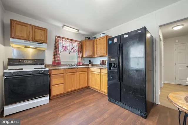 a kitchen with granite countertop a refrigerator stove and sink