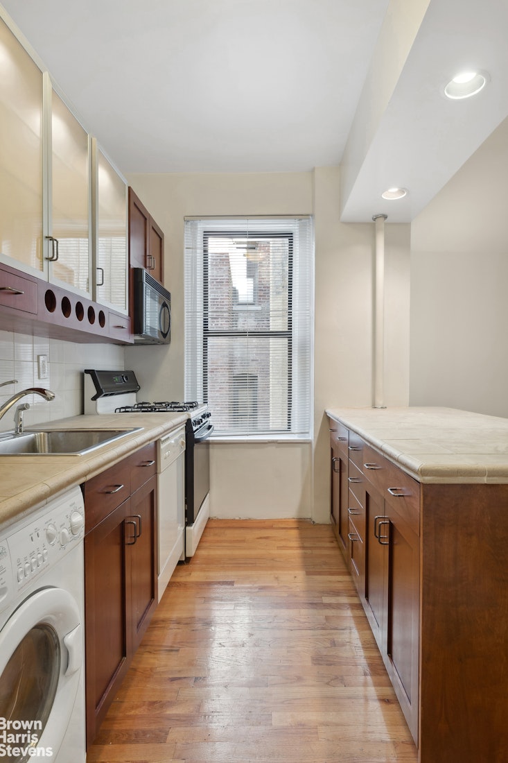 515 Edgecombe Avenue, Unit 41 Manhattan, NY 10032 - Photo 4 of 12 a large white kitchen with granite countertop a sink and dishwasher a stove with wooden floors