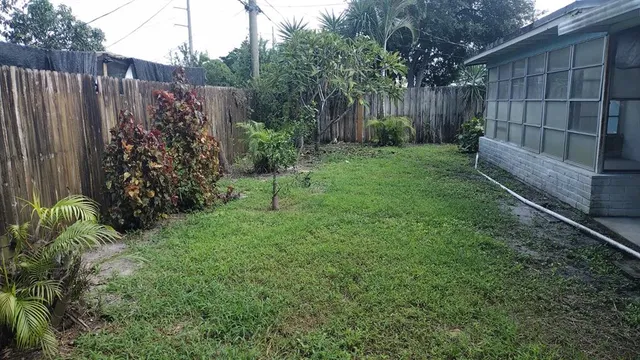 a view of a backyard with plants and wooden fence
