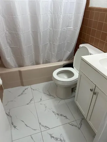 a white toilet sitting next to a white sink and vanity