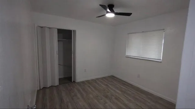 an empty room with wooden floor cabinet and windows