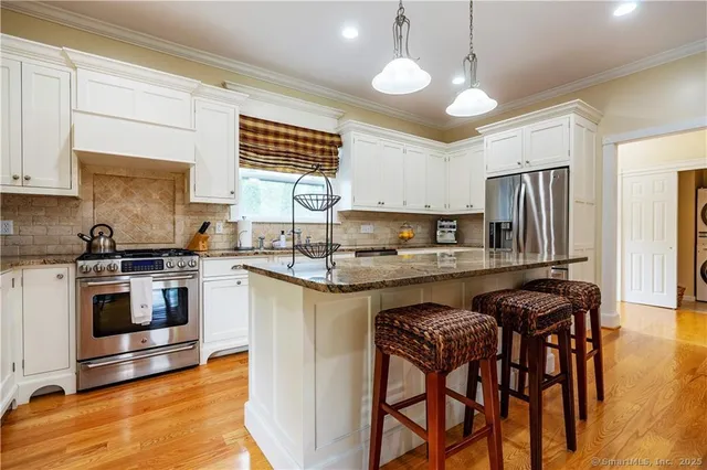 a kitchen with granite countertop wooden cabinets a stove a sink a oven a dining table and chairs