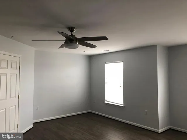 an empty room with a window and a ceiling fan