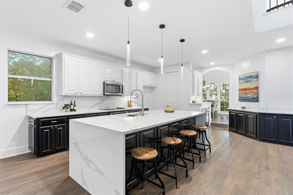 a kitchen with stainless steel appliances granite countertop a stove a sink a microwave a center island and a cabinets