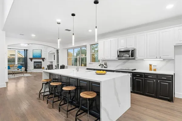 a large kitchen with stainless steel appliances granite countertop a stove a sink a dining table and chairs with wooden floor