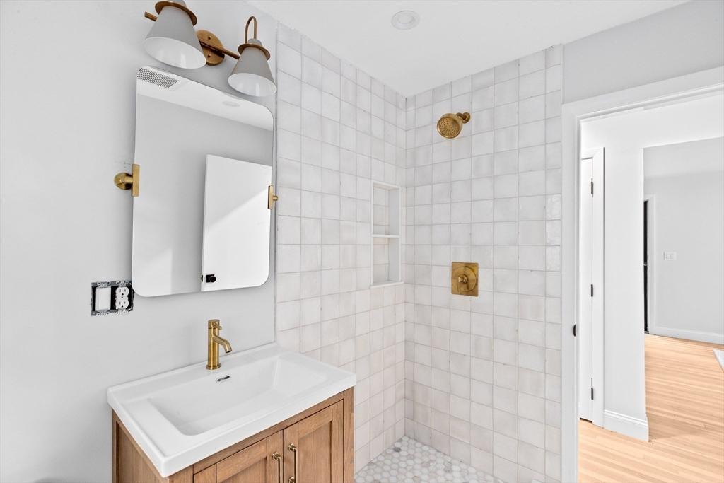 14 Spring Street Hingham, MA 02043 - Photo 16 of 28 a bathroom with a sink a mirror and shower