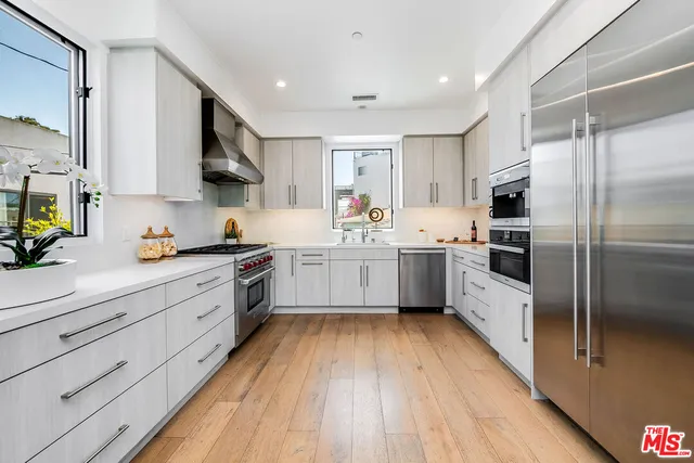 a kitchen with stainless steel appliances a sink cabinets and wooden floor