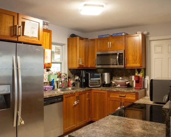 a kitchen with stainless steel appliances granite countertop a refrigerator a stove top oven a sink dishwasher and wooden cabinets