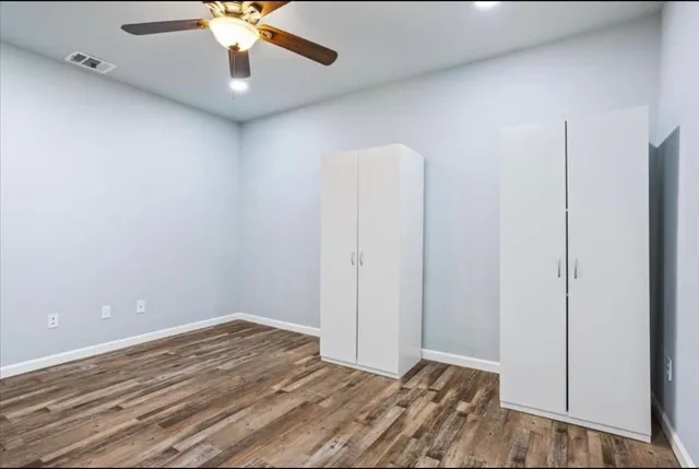 an empty room with a ceiling fan and wooden floor
