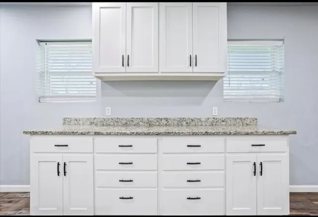 a kitchen with granite countertop white cabinets and a window