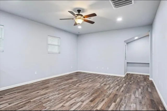 an empty room with a ceiling fan and wooden floor