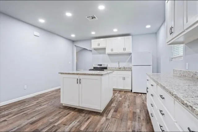 a kitchen with granite countertop white cabinets and white appliances