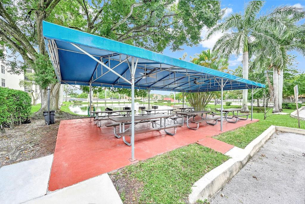 6195 Rock Island Road, Unit 215 Tamarac, FL 33319 - Photo 3 of 37 a view of a backyard with table and chairs under an umbrella