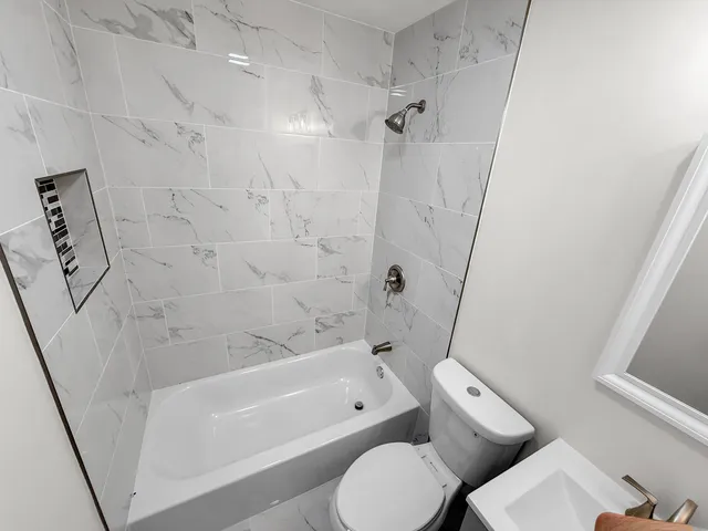 a bathroom with a bathtub shower sink vanity and toilet