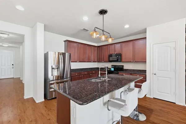 a kitchen with stainless steel appliances granite countertop a sink refrigerator and cabinets