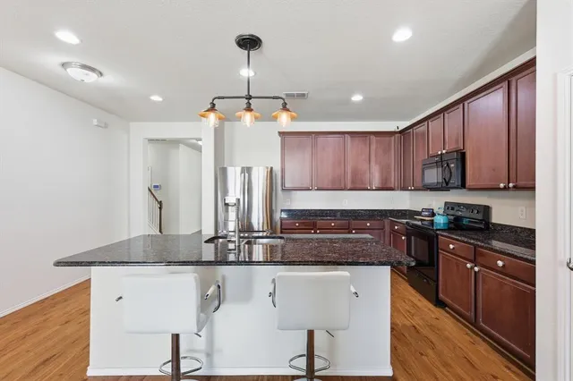 a kitchen with kitchen island granite countertop stainless steel appliances a sink a stove a counter space and cabinets