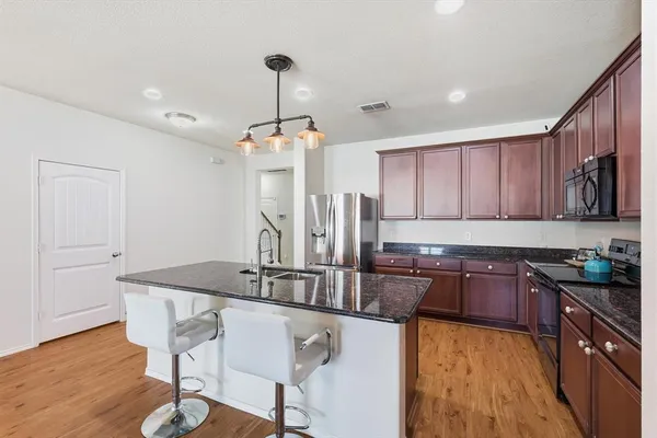 a kitchen with granite countertop a sink cabinets and wooden floor
