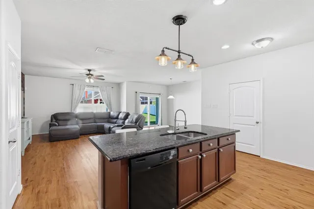 a kitchen with a counter space a sink and living room view