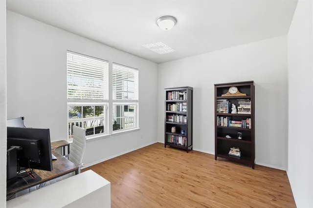a view of an empty room with a window and wooden floor