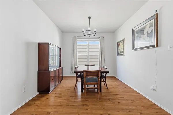 a dining room with wooden floor a chandelier a wooden table and chairs