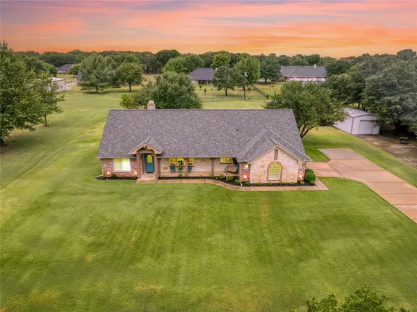 an aerial view of a house with pool big yard and large trees