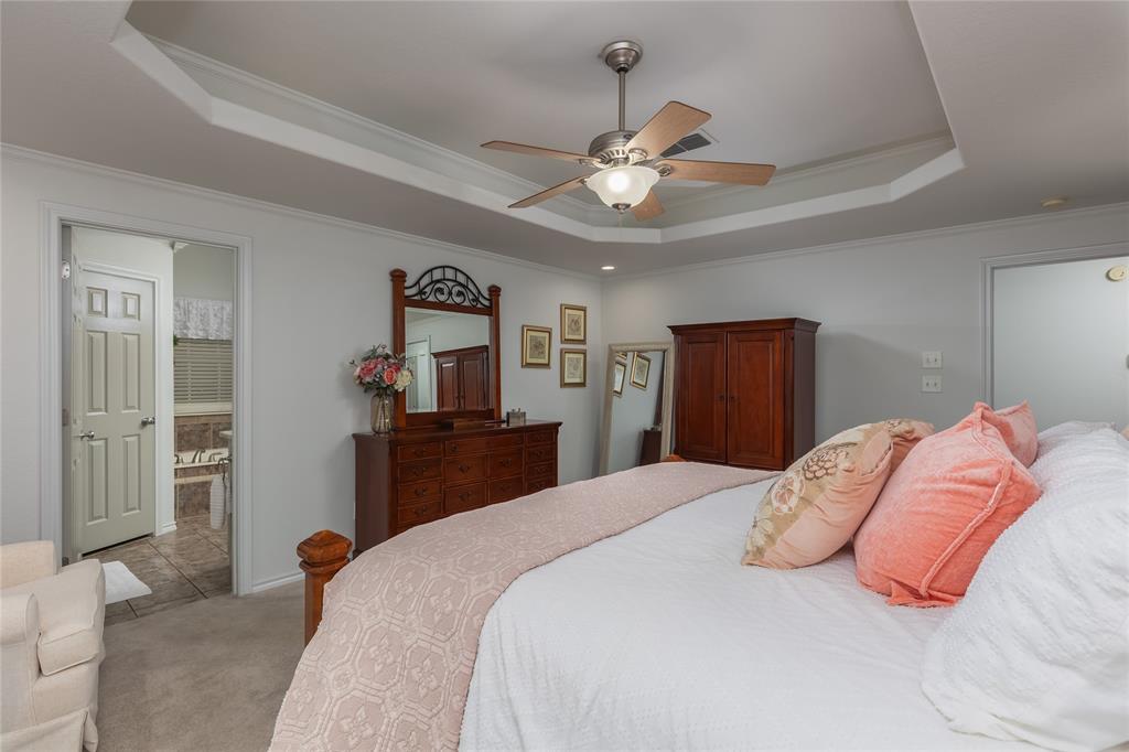 510 Highland Road Springtown, TX 76082 - Photo 19 of 40 a bedroom with a large bed and a chandelier