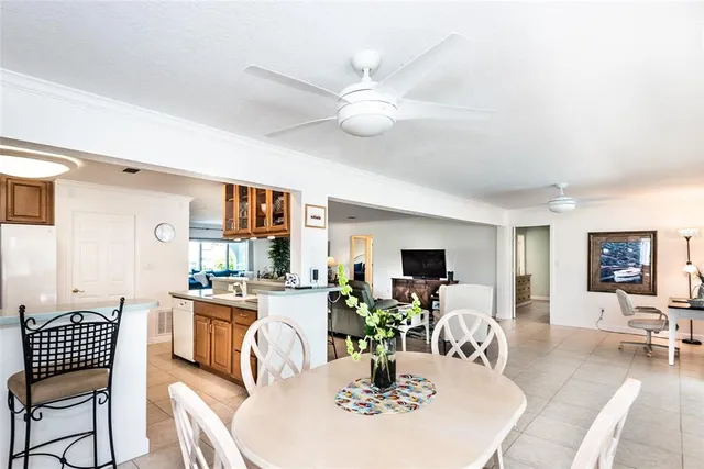 a dining room with wooden floor a chandelier fan a wooden table and chairs
