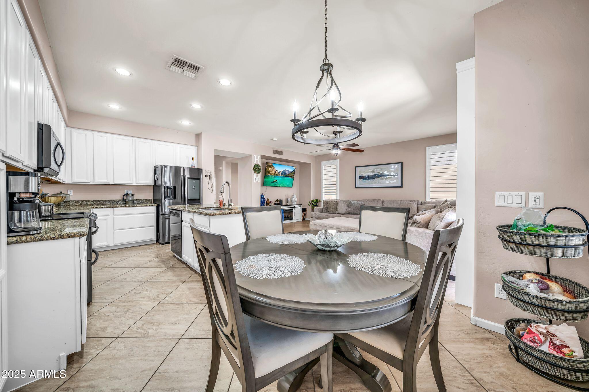 2292 South 155th Lane Goodyear, AZ 85338 - Photo 15 of 62 a view of a dining room and livingroom with furniture a chandelier and wooden floor