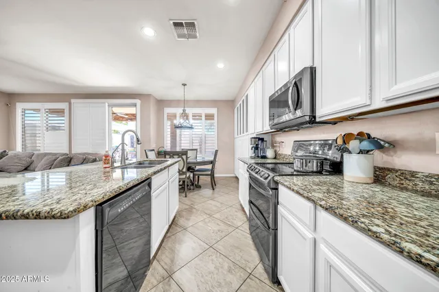 a kitchen with stainless steel appliances granite countertop a refrigerator a stove a sink dishwasher a dining table and chairs with wooden floor
