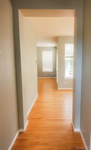a view of a hallway with wooden floor and a bathroom