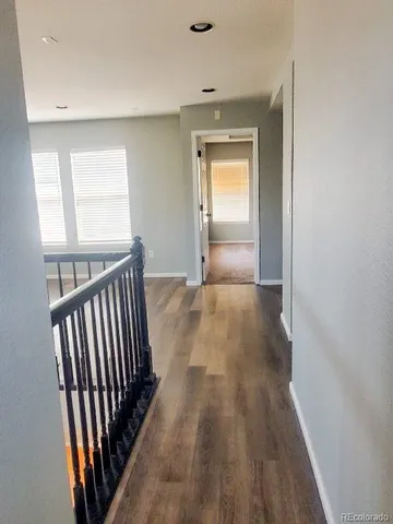 a view of a hallway with wooden floor and a bathroom