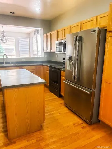 a kitchen with stainless steel appliances granite countertop a refrigerator a sink and a stove