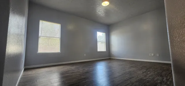 an empty room with wooden floor and windows