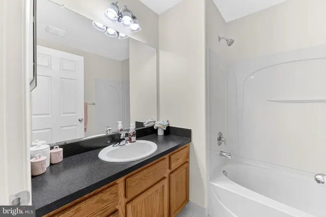a bathroom with a granite countertop sink a toilet a mirror and shower
